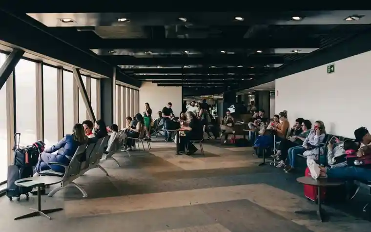 공항 터미널 의자에 앉아 비행기를 기다리는 승객들