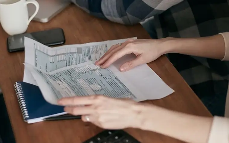 서류와 노트를 함께 펼쳐 놓고 내용을 확인하는 손