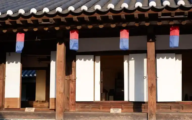 붉은 담과 기와지붕이 이어진 골목의 오래된 한옥 건물 앞면