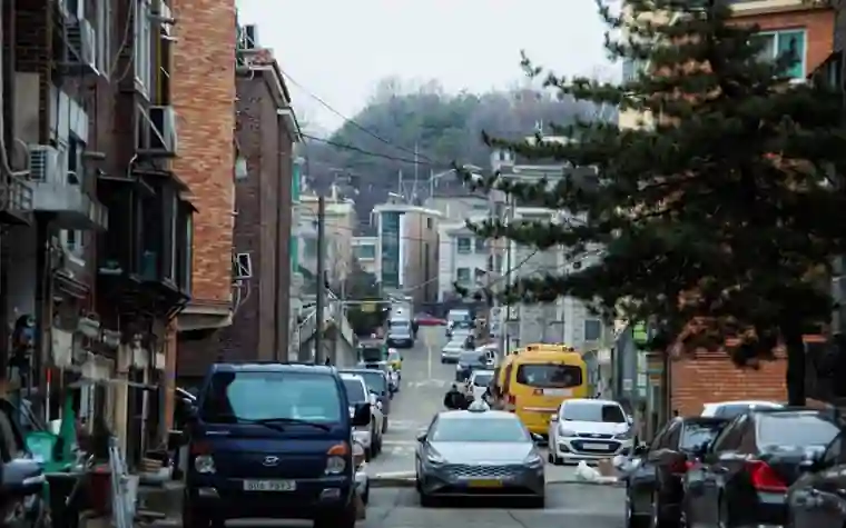 좁은 골목 양옆으로 빌라와 주차된 차들이 늘어선 주택가 풍경