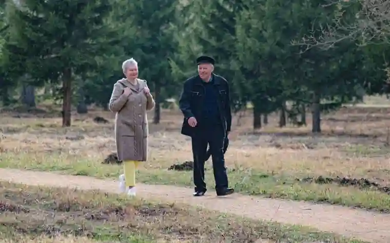 공원 산책길을 나란히 걸어가는 노부부의 모습
