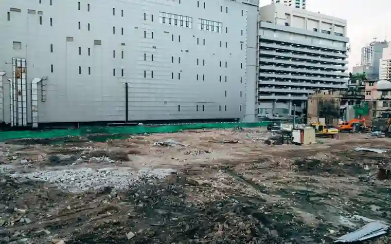 철거가 끝나 흙과 잔해만 남은 도심 부지와 옆의 대형 건물