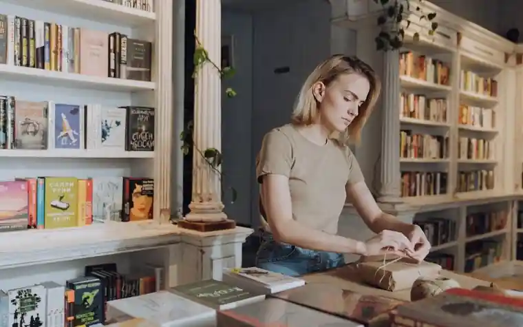 작은 책방에서 손님에게 줄 책을 포장지로 정성스럽게 포장하는 사장님