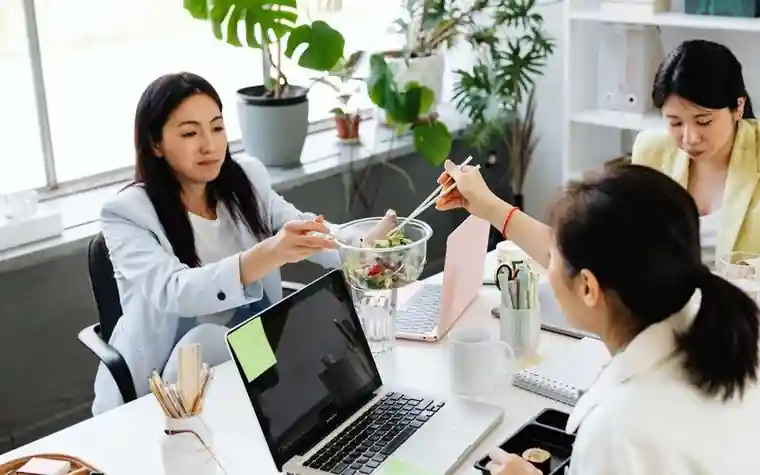 사무실에서 점심을 먹으며 대화하는 직장인들